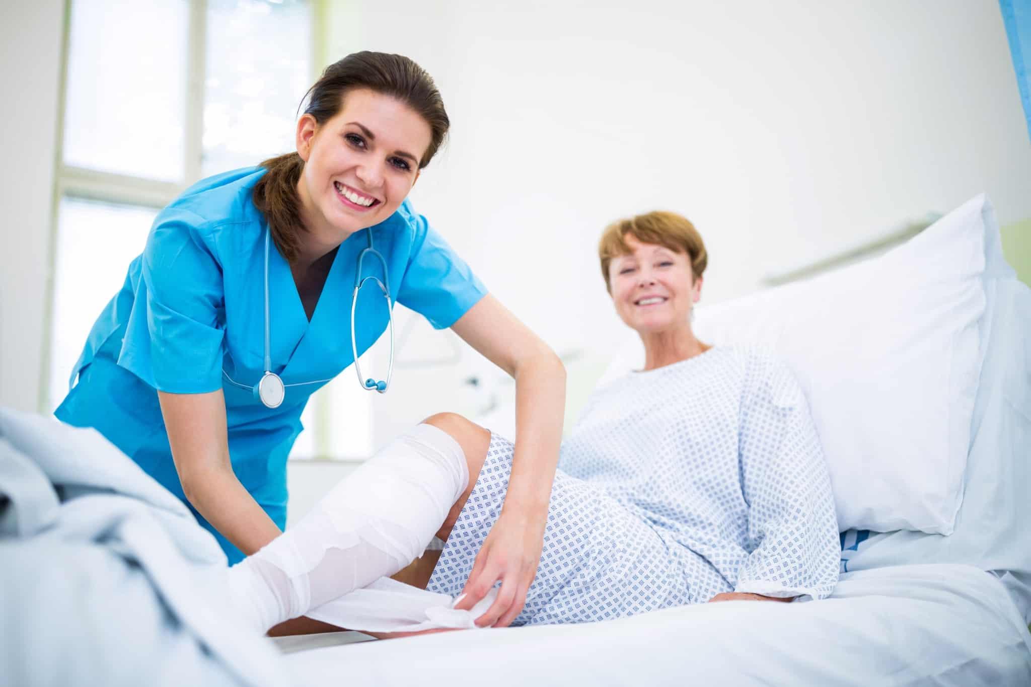 Smiling healthcare professional bandaging a patient's leg